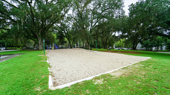 a sand volleyball court with trees in the background